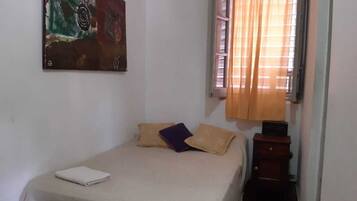 A bedroom with a bed, a nightstand, a window with curtains, and a painting on the wall.