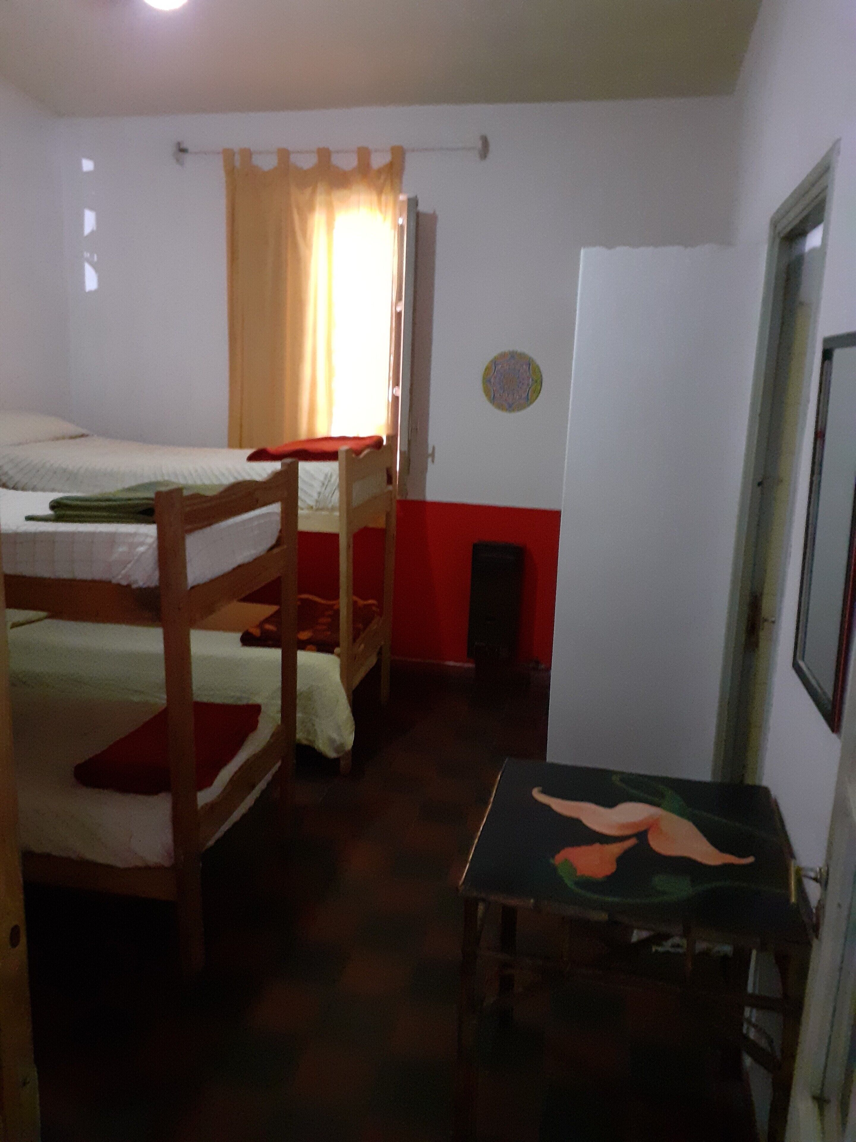 Un dormitorio con literas, una mesita pequeña y una puerta.