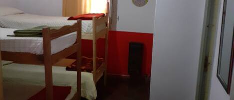 Un dormitorio con literas, una mesita pequeña y una puerta.