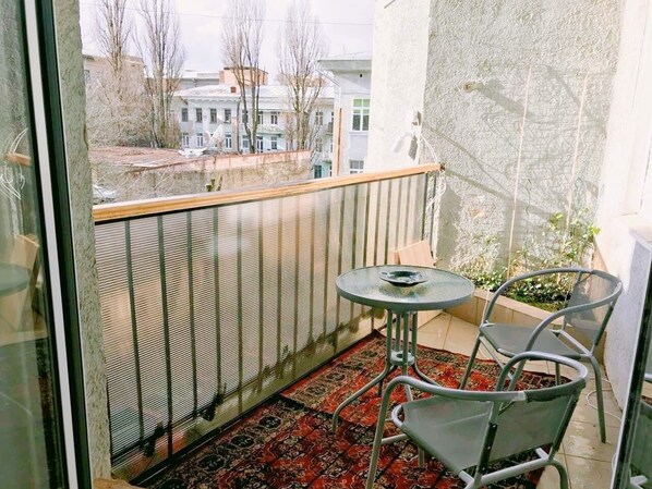 A balcony with a metal railing, a small round table, and two chairs.