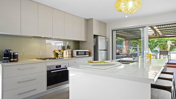 A modern kitchen with a large island, stainless steel appliances, and a view of the outdoors.