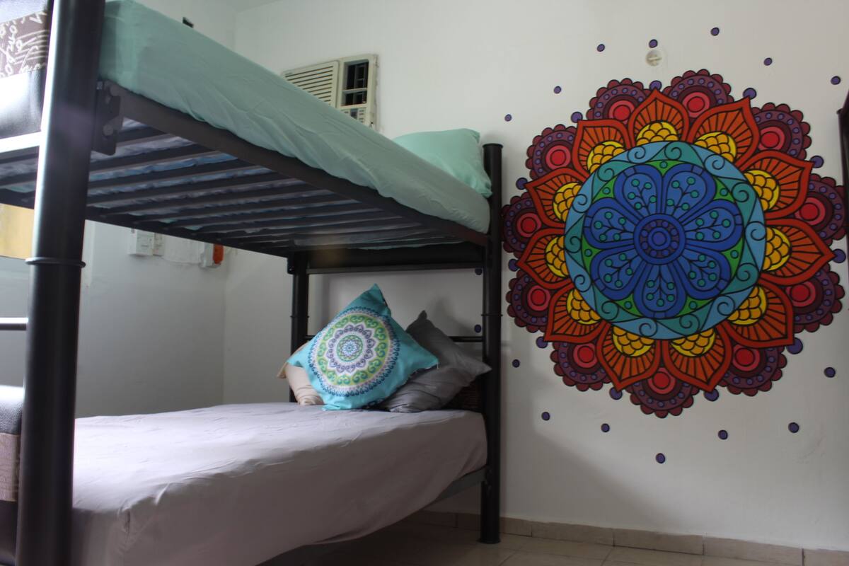 Ein Etagenbett mit blauer Matratze und farbenfroher Wandgestaltung mit einem Mandalas.