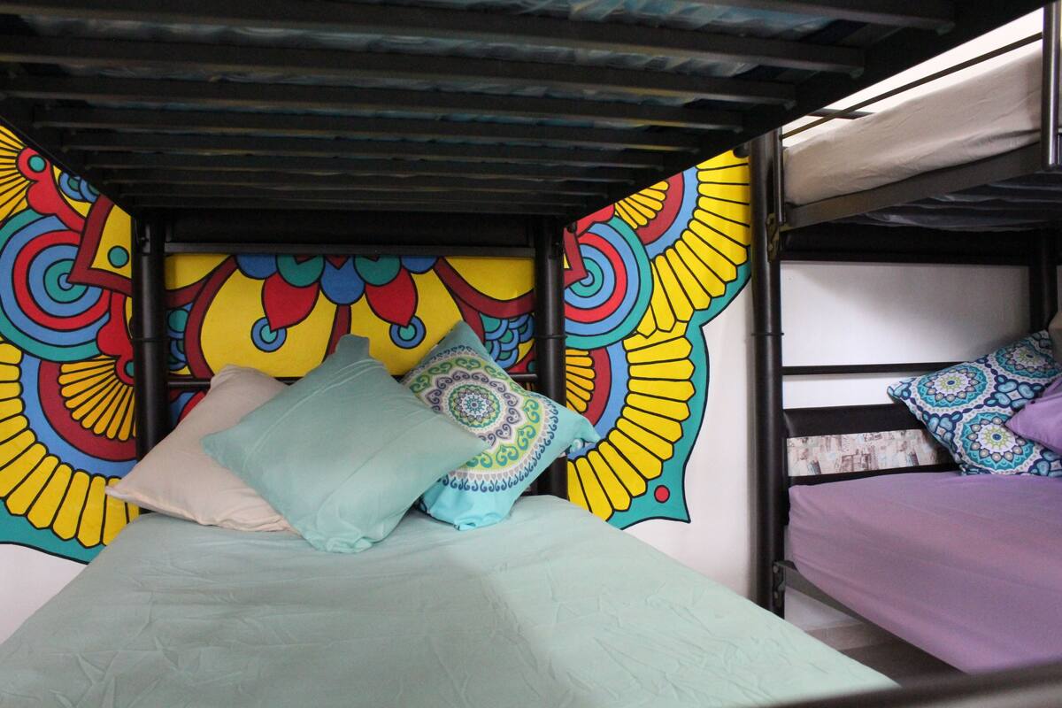 Ein Stockbett mit einem farbenfrohen Wandgemälde im Hintergrund.