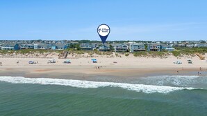Vista de la playa con casas al fondo y un marcador de ubicación para Village Realty.