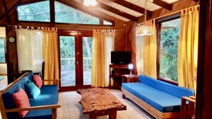 Una habitación acogedora con un sofá azul, una mesa de madera y un televisor sobre un mueble.