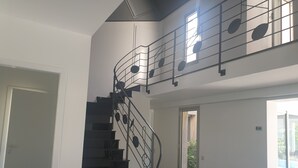 Un escalier avec une rampe en métal et une vue sur l’extérieur grâce à une porte vitrée.