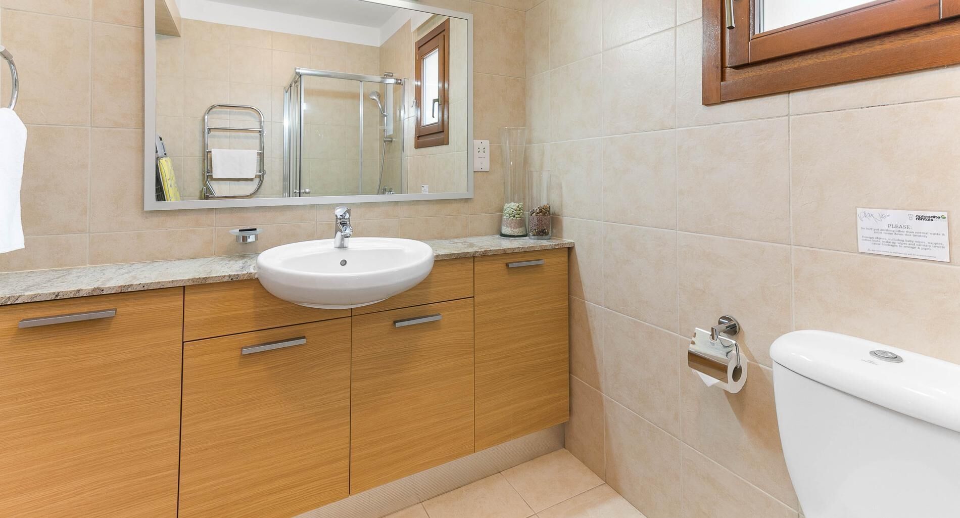 Un baño con lavamanos, espejo e inodoro.