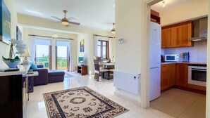 A spacious living area with a sofa, a dining table, and a kitchen with wooden cabinets and modern appliances. - Apartment A12 - Nesoi (Kouklia)