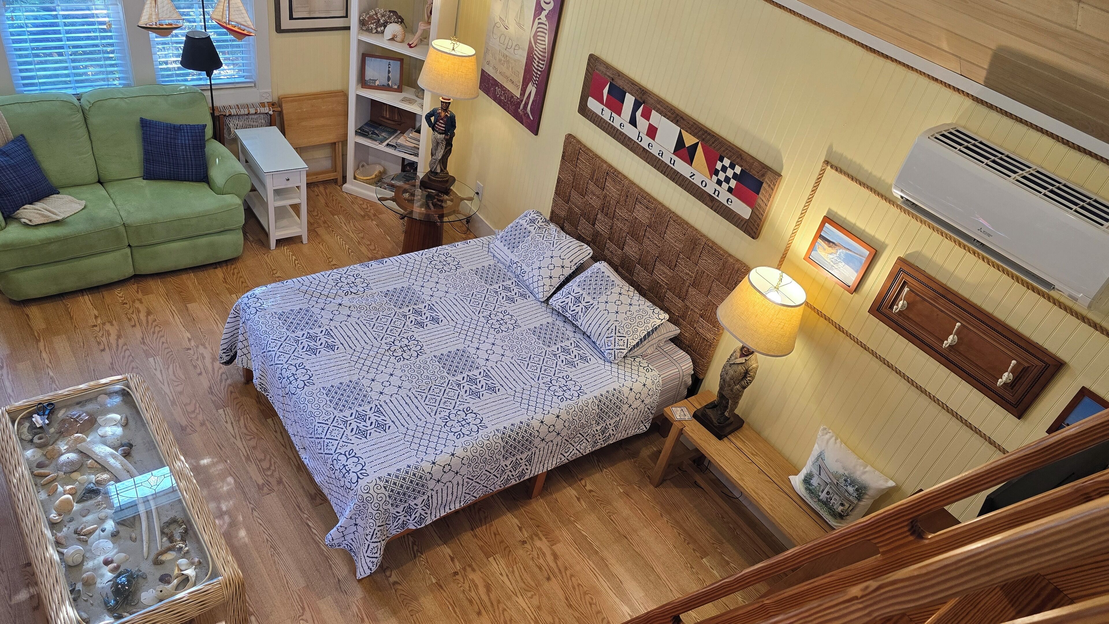 A cozy room with a bed, a green sofa, a small table, and a bookshelf.