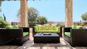 A patio area with wicker furniture, a green sofa, and a coffee table.