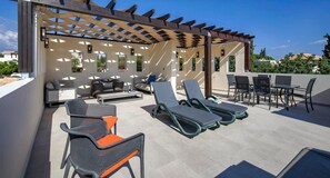 An outdoor patio with seating, a pergola, and a table with chairs.