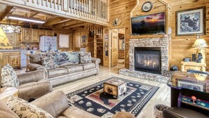 A cozy log cabin interior with a fireplace, wooden furniture, and a balcony. - Located 1.5 mi. from the Parkway in Pigeon Forge. (Pigeon Forge)