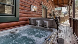 A wooden cabin with a hot tub, a welcome sign, and a deck. - Located 1.5 mi. from the Parkway in Pigeon Forge. (Pigeon Forge)