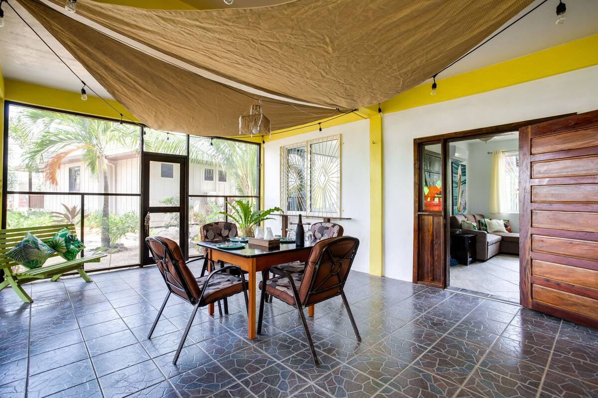 A dining area with a table and chairs, large windows, and a view of the outdoors.