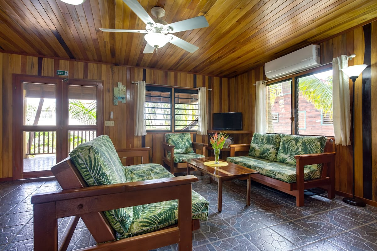 A wooden interior with a ceiling fan, a TV, and a seating area with a table and chairs.