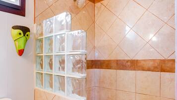 A shower with a glass enclosure and a decorative mask on the wall.