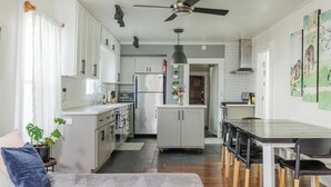 A modern kitchen with white cabinets, a central island, and a dining area with a table and chairs.