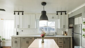 A modern kitchen with white cabinets, a central island, and a hanging pendant light.