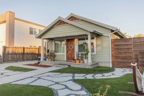A house with a front porch, a wooden door, and a number '45771' on the door. There is a wooden fence to the right and a paved driveway leading to the house. - Cozy Central Family Home - Beaches/Zoo/Balboa Park (San Diego)