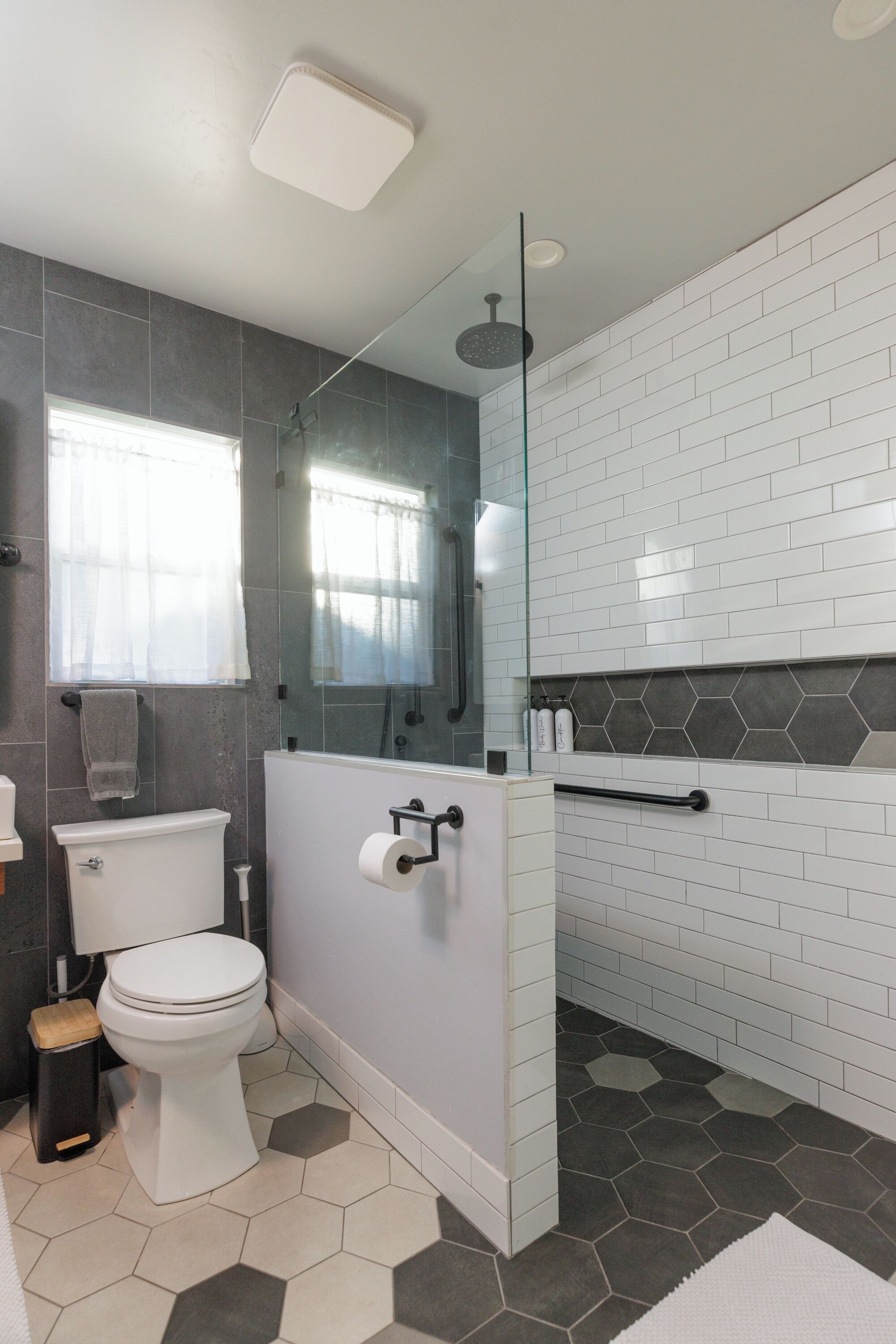 Une salle de bain moderne équipée de toilettes, d’une douche et d’un espace douche délimité par des parois en verre.