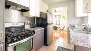 Una cocina moderna con electrodomésticos de acero inoxidable, armarios blancos y una encimera de granito.