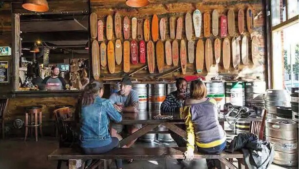 Un interior rústico con paredes de madera, una hilera larga de palas de madera y barriles metálicos.