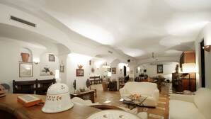 A spacious living room with high ceilings and arched doorways, featuring a wooden coffee table, a cream-colored sofa, and a dining area in the background. - AMORE RENTALS - Villa Angelo with Private Terraces, Parking and Air Conditioning (Sant´Agnello)