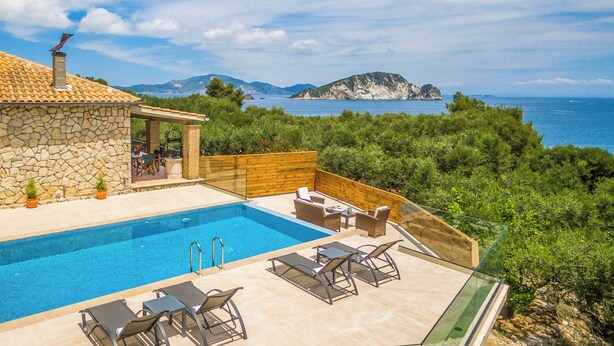 A poolside area with a stone building, wooden deck, and lounge chairs.