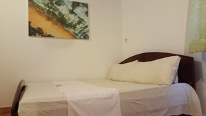 Una cama individual con cabecera de madera en una habitación con pared blanca lisa.
