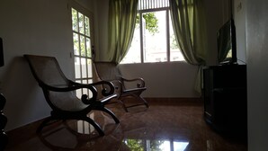 Una habitación con dos mecedoras, un televisor y una ventana con cortinas.
