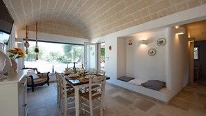 Un espace repas doté d’un plafond en briques, de murs blancs et offrant une vue sur l’extérieur.