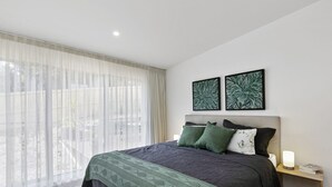 Ein modernes Schlafzimmer mit einem großen Bett, einem Nachttisch und zwei an der Wand befestigten Kunstwerken.