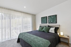 Een moderne slaapkamer met een groot bed, een nachtkastje en twee kunstwerken aan de muur.