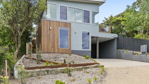 A modern two-story house with a wooden facade, large windows, and a landscaped garden. - Seahaven - Brilliant Location, Stunning Modern Features (Lorne)