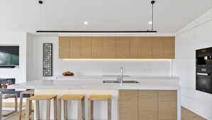 Eine moderne Küche mit einer zentralen Kochinsel, Holzschränken und einem eingebauten Backofen.