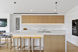 Een moderne keuken met een centraal eiland, houten kastjes en een ingebouwde oven.