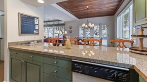 Una cocina con encimera de granito, techo de madera y lavavajillas.
