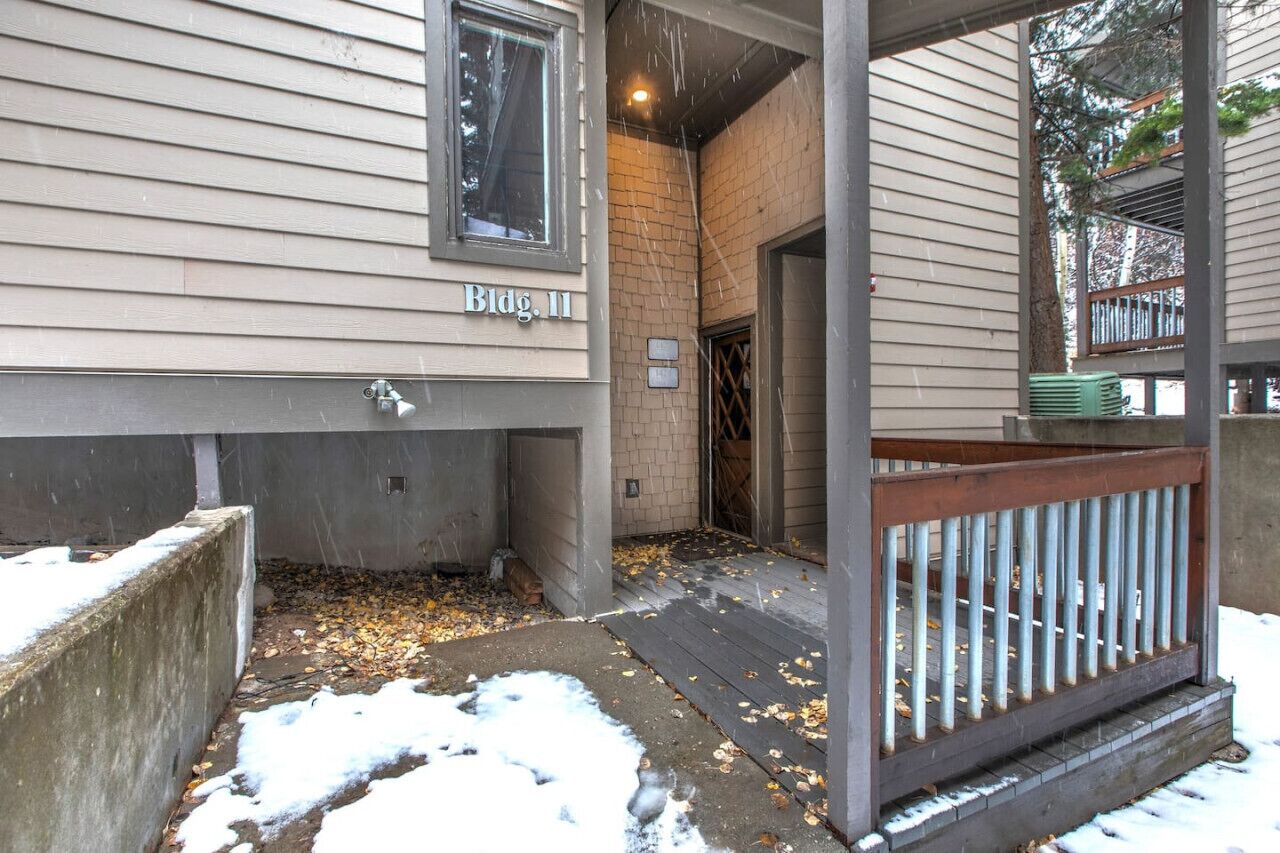 A residential building with a concrete foundation, a wooden deck, and a brick wall.