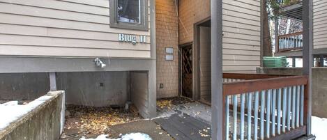 A residential building with a concrete foundation, a wooden deck, and a brick wall.
