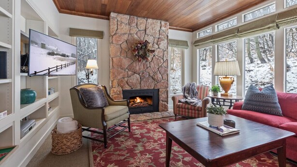 Una sala acogedora con chimenea de piedra, televisor y asientos cómodos.