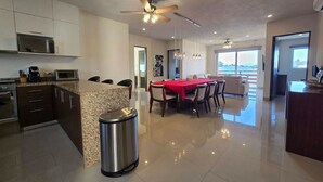 A modern kitchen with a granite countertop, stainless steel appliances, and a dining area with a red tablecloth.