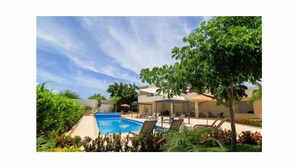 A pool area with lounge chairs and a clear sky.