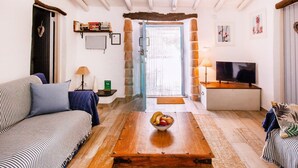 A cozy living room with a sofa, a coffee table with fruit, a TV, and a stone wall. - The Casita Spain Huércal-Overa by Ruralidays (Almería)