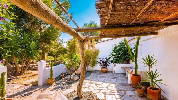 A courtyard with stone flooring, potted plants, a wooden pergola, and a thatched roof structure. - The Casita Spain Huércal-Overa by Ruralidays (Almería)