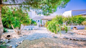 A courtyard with a stone pathway, potted plants, and a white building with a tiled roof. - The Casita Spain Huércal-Overa by Ruralidays (Almería)
