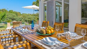 A wooden dining table set with plates, glasses, and a fruit bowl. - Villa Valparaiso Alhama de Granada by Ruralidays (Granada)