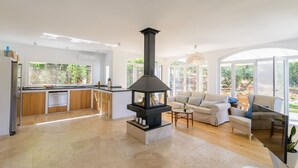A modern kitchen with a central island, a built-in stove, and a dining area with a round table and chairs. - Villa Valparaiso Alhama de Granada by Ruralidays (Granada)