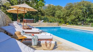 A poolside area with lounge chairs, a hot tub, and a stone wall. - Villa Valparaiso Alhama de Granada by Ruralidays (Granada)