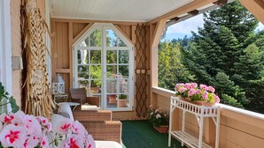 Een gezellig balkon met rieten meubels, een witte stoel en bloempotten.