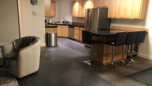 Cozinha moderna com geladeira de aço inoxidável, armários de madeira e bancada com banquetas.